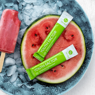 Neora's Youth Factor Antioxidant Powder laying atop a watermelon next to a popsicle